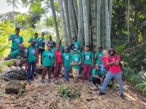 Groupe de jeunes et de professionnels qui prennent la pose devant un bosquet de bamboo en pleine nature