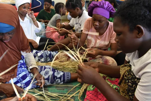 Jeunes filles qui fabriquent des trucs avec des feuilles de cocotier.