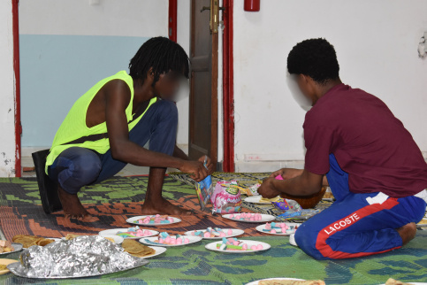 Deux jeunes accroupis qui installent les assiettes pour le ftour